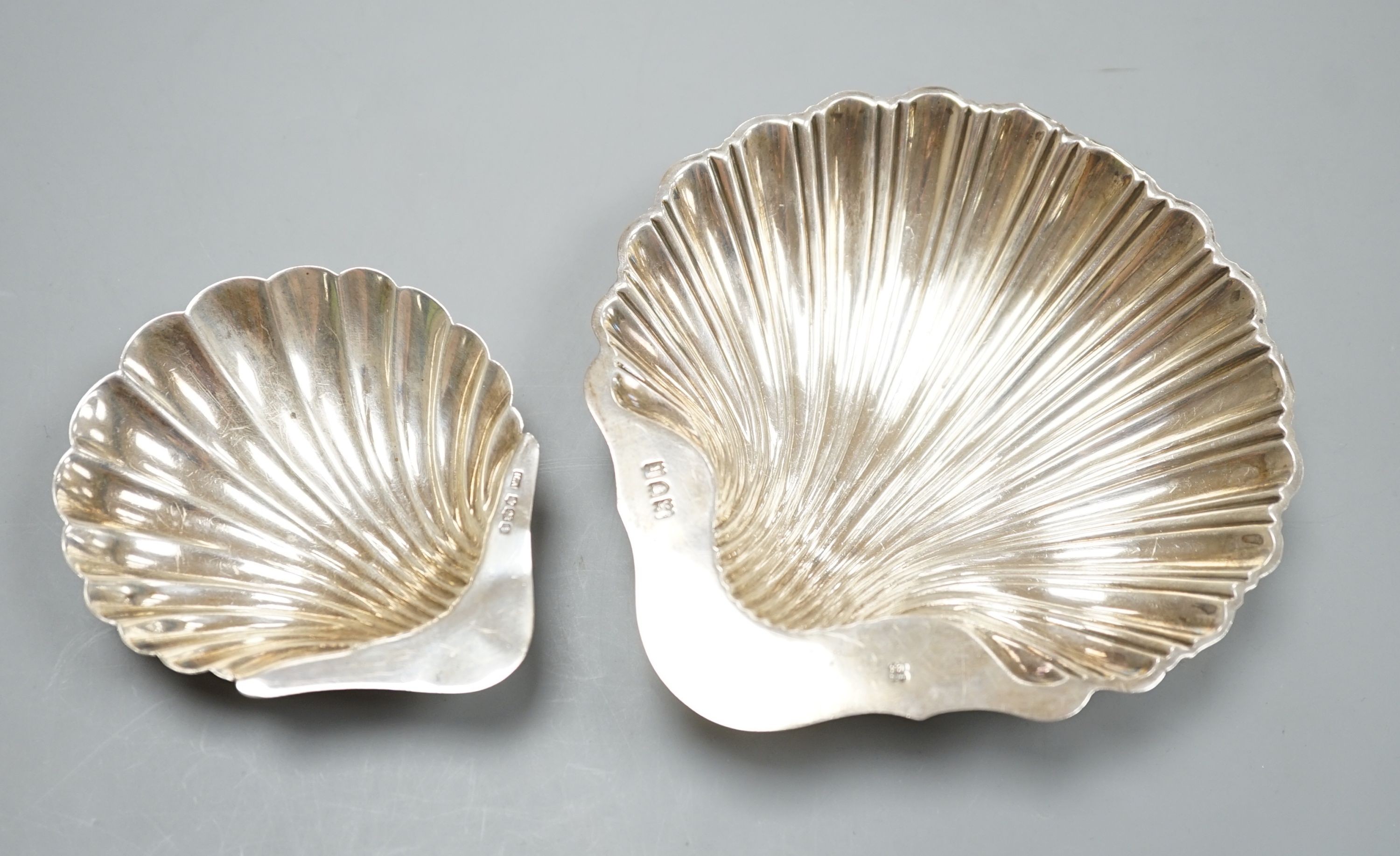 A scallop shell butter dish on three ball feet, Sheffield 1926, 94mm and an earlier larger silver butter shell, London, 1905, 112 grams.